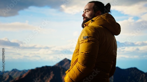 Quadro su tela A trekker in warm clothing admires a sweeping mountain view at high altitude, enjoying fresh air and a sense of freedom while exploring the scenic wilderness during an adventurous journey
