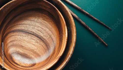 Cozy wooden bowl with chopsticks on teal surface.