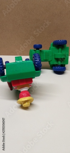 Foto Two overturned green plastic toy tractors on white surface mac donald