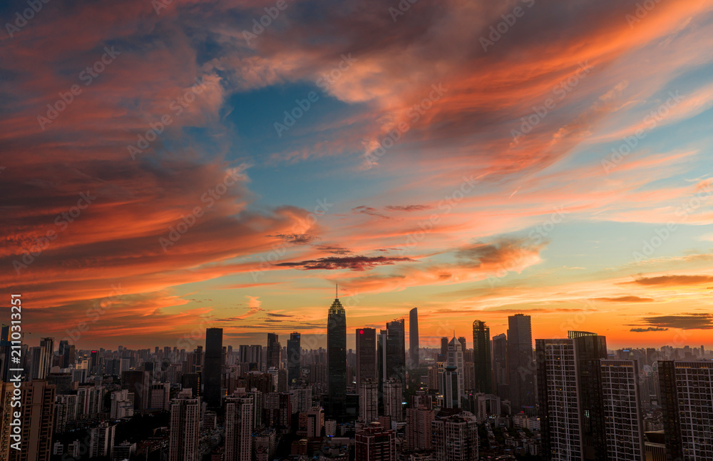Fototapeta premium Wuhan CBD skyline illuminated by a dramatic fiery sunset. These brilliant burning clouds above towering skyscrapers symbolize a blazing, prosperous economy and the dawn of a dynamic financial future.