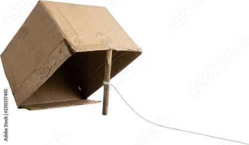 Homemade cardboard box trap propped open by a wooden stick and string showing the inside of the structure DIY craft twine bait capture animal trap snare hunter survival wilderness