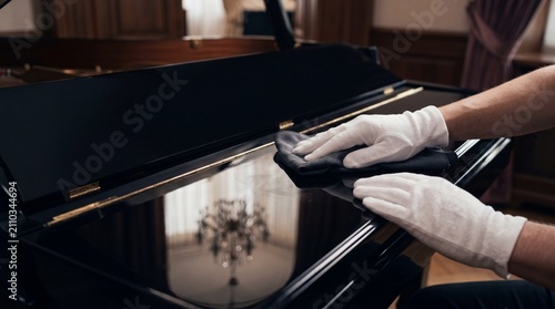 Professional piano cleaning and maintenance with white gloves