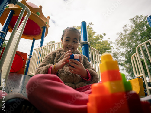 Outdoor playground scene with a child holding a toy