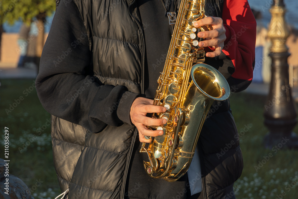Obraz premium Unrecognizable street musician playing golden alto saxophone close up