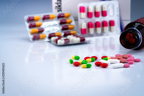 Fotografie Tablets and capsules pills on white table and blurred drug bottle, blister pack, and antibiotic drug box