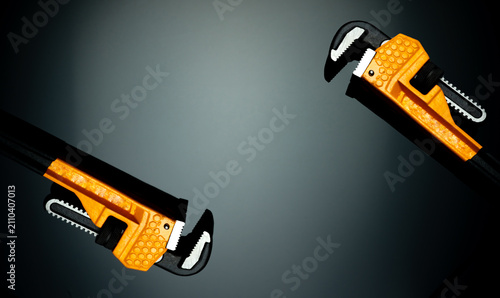 Foto Set of new chrome pipe wrench with yellow handle isolated on dark background
