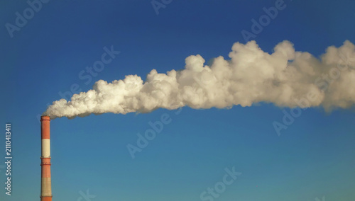 Industrial chimney releasing smoke into clouds.