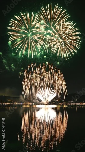 Vibrant fireworks illuminating the night sky above dark water reflection