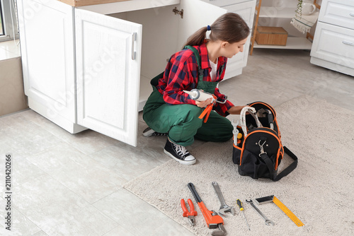 Young female plumber in ove...