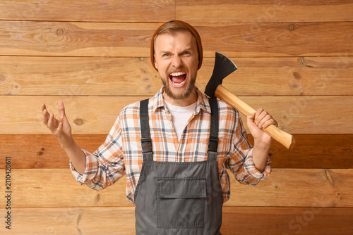 Photography Angry lumberjack with an axe and open mouth screaming, wearing a plaid shirt and