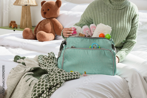 Woman with baby bag sitting in bedroom