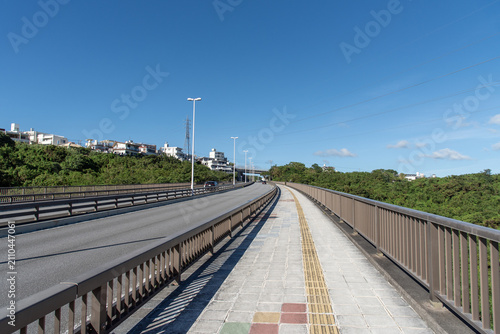 快晴の空と橋の点字ブロックが続く歩道と車道