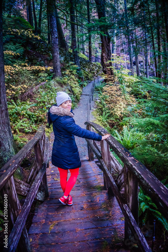 Obraz na płótnie Woman walks wooden bridge through forested trail