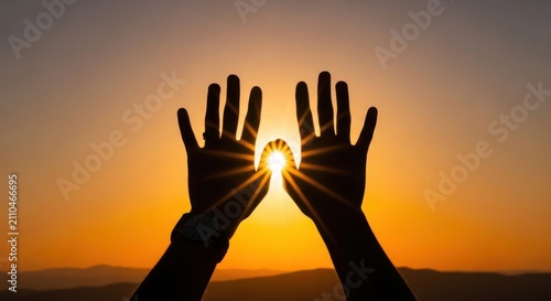 Silhouette of two hands reaching up towards the bright sun during a golden sunset