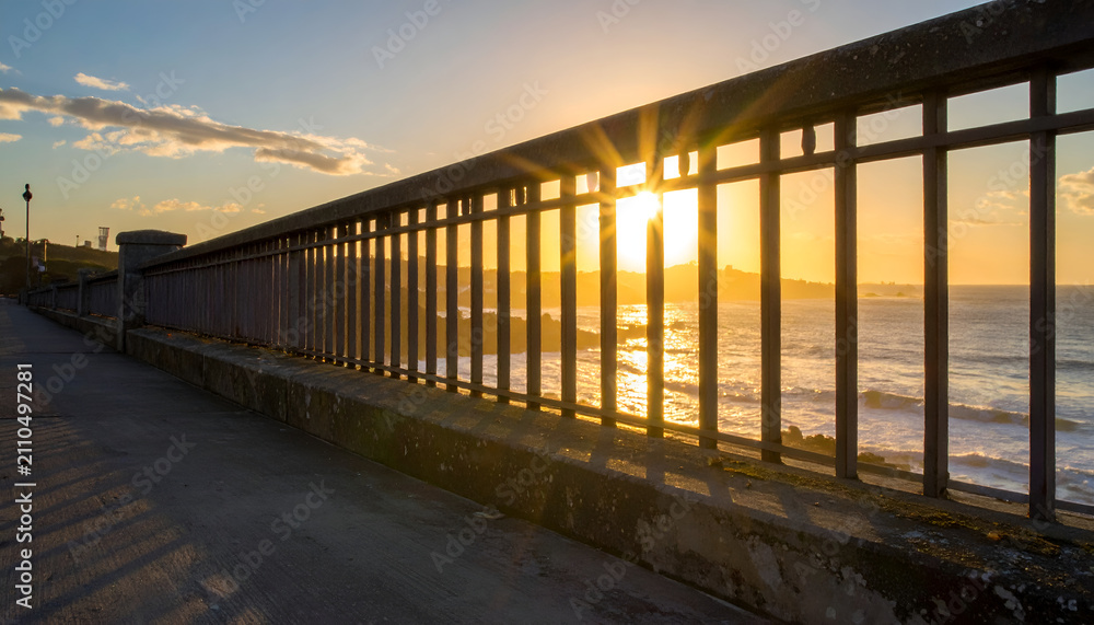 Obraz premium Sunset View Over Ocean Behind Fence on Coastal Path