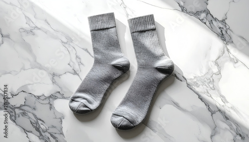Gray ribbed crew socks laid flat on a marble surface with natural light casting shadows
