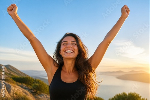 Woman celebrating with arms raised on mountain overlook sunset