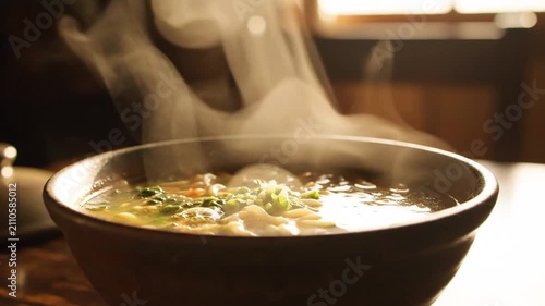 Steaming Hot Bowl of Savory Soup with Fresh Garnish, Close-up View
