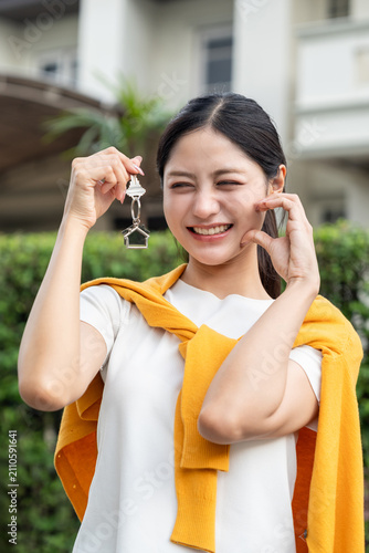 Canvas Print Happy young woman holding house keys in front of new home