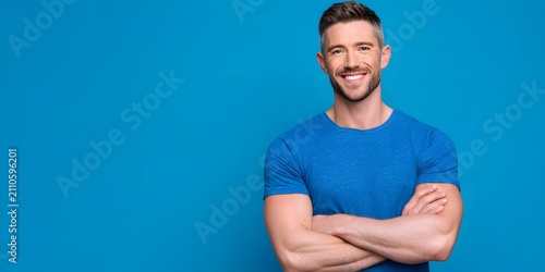Smiling man with arms crossed against a blue background.