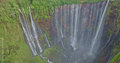 Scenic aerial photography of Indonesia's stunning Tumpak Sewu Waterfall, a world-class travel destination surrounded by lush greenery, volcanic terrain, and dramatic waterfalls.