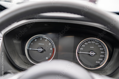 An analog car with traditional dashboard showing the speedometer and tachometer gauges through the steering wheel, needles at zero, showing the vehicle is not running