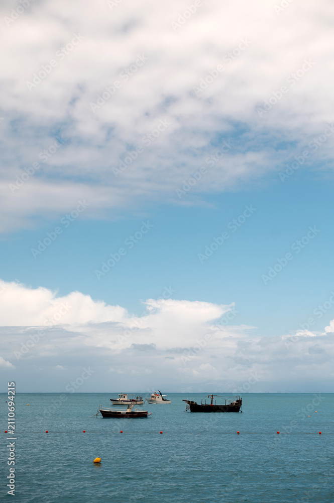 Fototapeta premium Several boats anchored in the calm blue sea under a cloudy sky