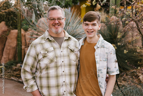 Fotografía Happy father and teenage son smiling in a garden