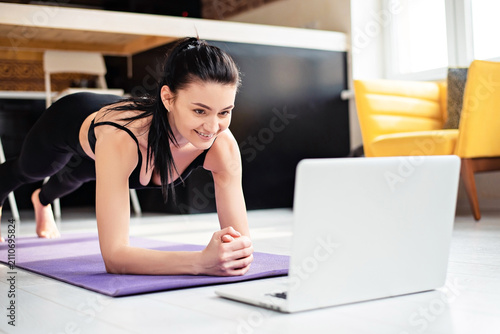 Canvas Print Smiling woman using laptop for training at home