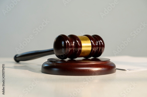Bild auf Leinwand Wooden gavel rests on a round base with a sheet of paper nearby in a courtroom s