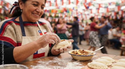 Scene at a Chilean food fair. A woman forming dough for empanadas with a blurred celebration in the background.