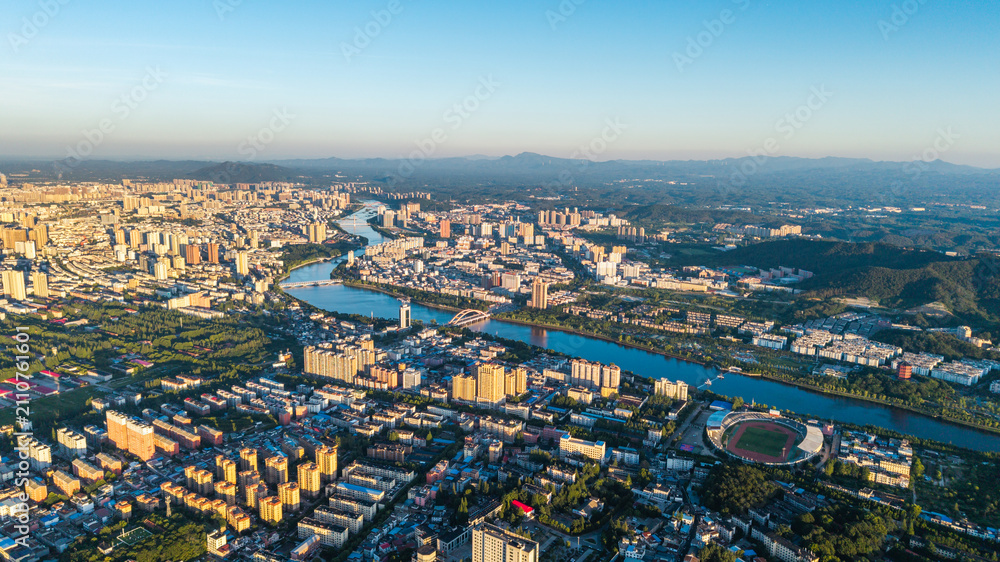 Fototapeta premium Xinyang city panoramic view with river flowing through urban landscape at golden hour