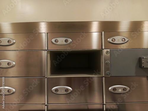 Open empty safety deposit box inside a secure bank vault with stainless steel metal lockers.