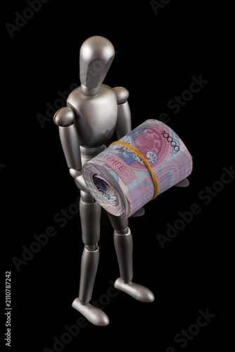 Принти на полотні A symbolic wooden man holds a stack of 10,000 Kazakhstani tenge banknotes against a black background