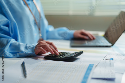 Fotografía Female accountant using a calculator while working on financial documents and a
