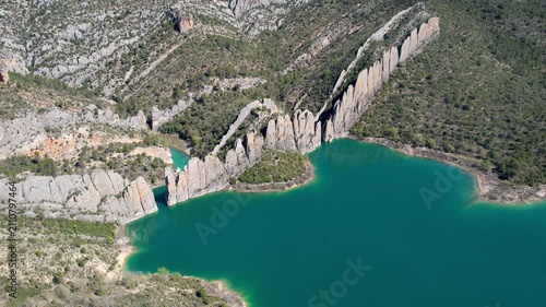 Orbital aerial shot of Muralla de Finestres and Canelles Reservoir on sunny spring day. Huesca, Aragon, Spain.