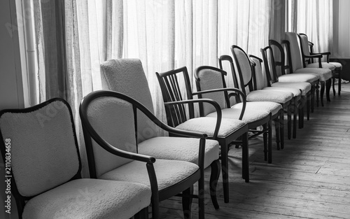 Obraz na plátne Elegant row of vintage chairs by sunlit windows in a minimalist interior