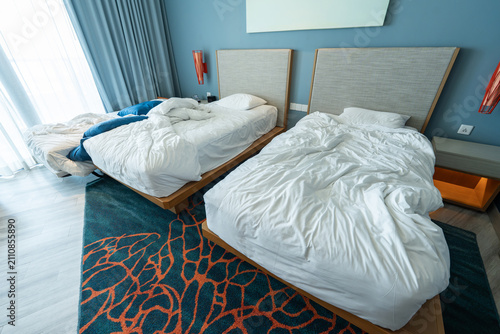 Foto Twin beds and a rollaway extra bed with untidy bedding, a recently occupied family hotel room