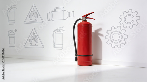 Red fire extinguisher standing in front of safety icon sketches on white wall