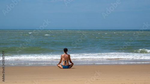 Femme assise en position de yoga face à l'océan atlantique sur la plage de la pointe Espagnole dans le département de Charente Maritime