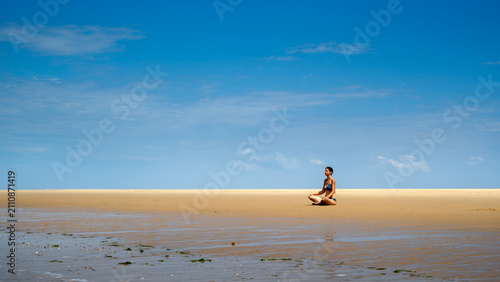 Femme assise en position de yoga face à l'océan atlantique sur la plage de la pointe Espagnole dans le département de Charente Maritime