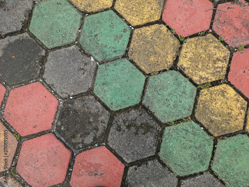 Textured red and green hexagonal stone pavers create a weathered pavement surface Abstract Background Concept Design