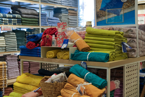 Neatly arranged bed linens, towels and home textile products displayed on shelves in a modern home goods store. Interior of a retail shop with household essentials for sale