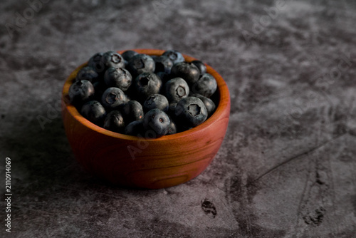 Blueberries in Small Wooden Bowl on Textured Stone Surface