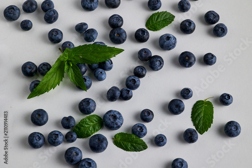 Scattered Fresh Blueberries with Mint Leaves on White Surface