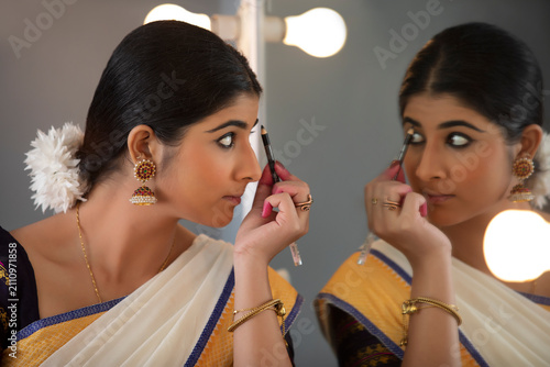 Classical dancer shading her eye brows in front of the mirror