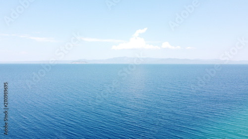 Deep Blue Sea Waters with Island Horizon and Clouds, Aerial View