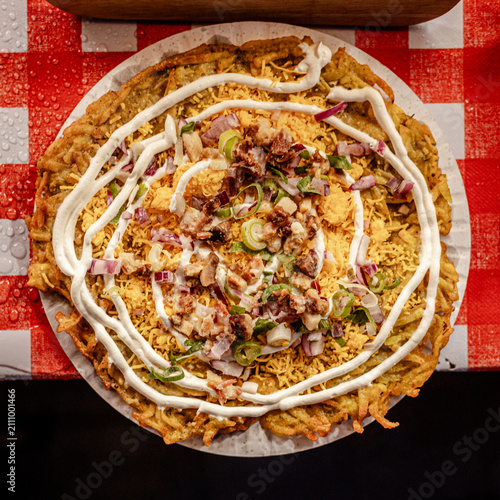 Crispy fried dish topped with shredded cheese, onions, and white sauce