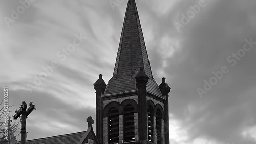 Black and white time lapse of a church steeple with dramatic clouds moving in the sky.