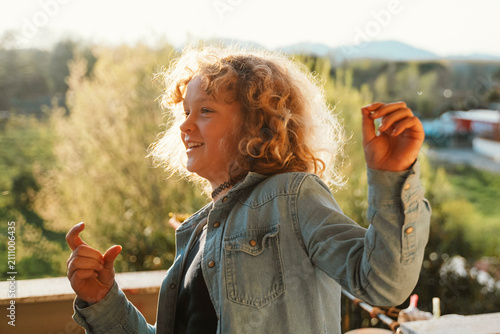 Cuadro en lienzo Young girl with curly hair smiling joyfully while enjoying outdoor sunshine on a bright day